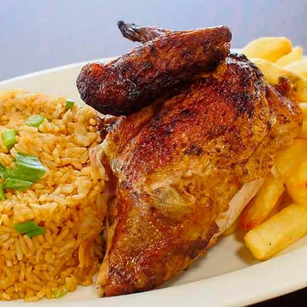 Peruvian roasted chicken with crispy skin, served with golden french fries and seasoned rice.