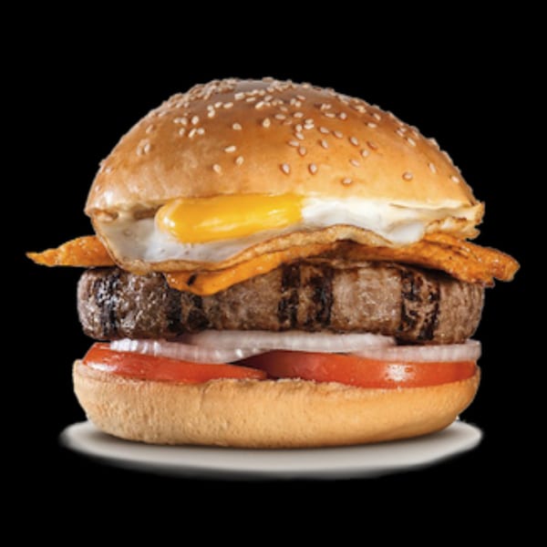 Peruvian-style burger with a thick patty, fried egg, cheese, bacon, tomato, and onion.